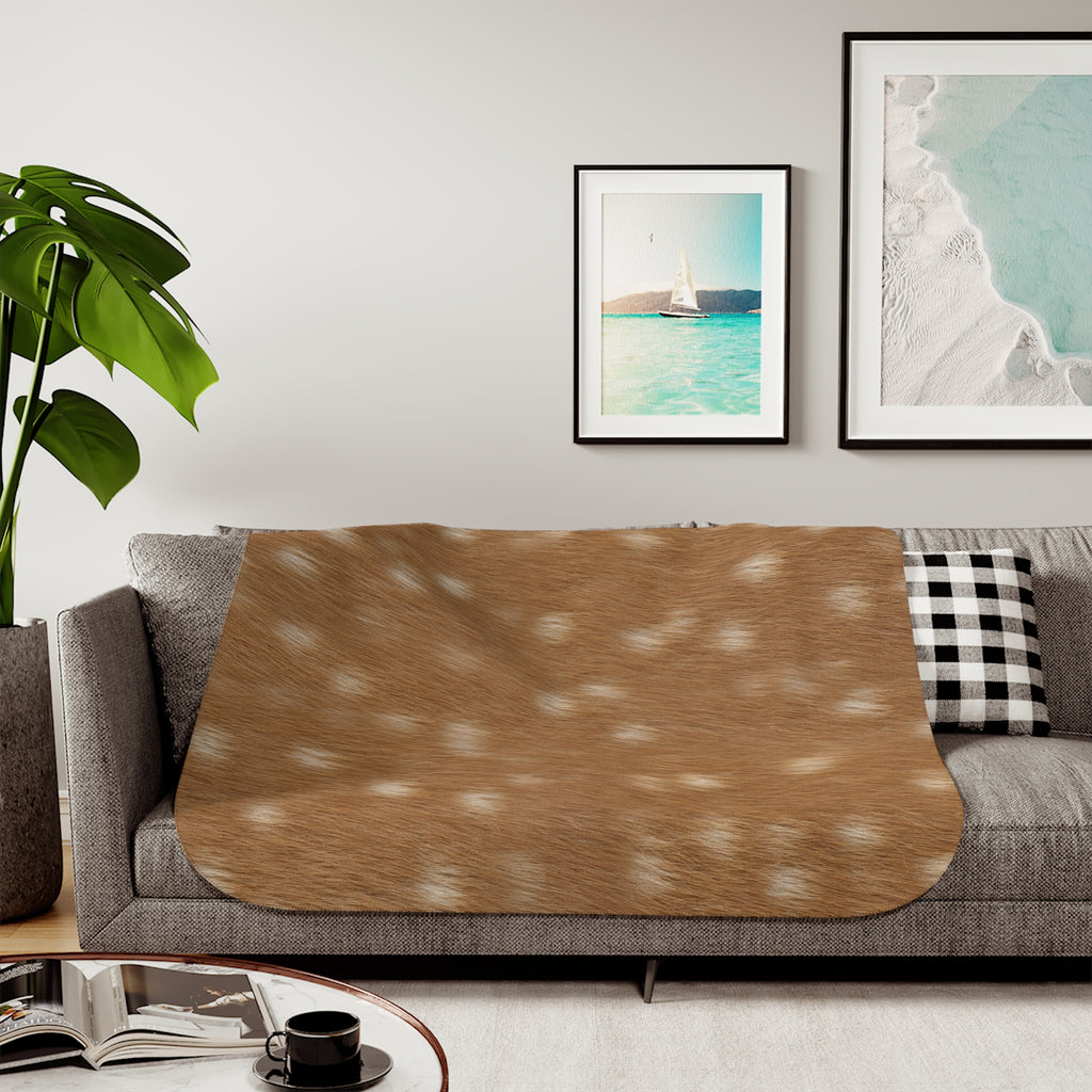 Spotted deer print sherpa blanket styled on a neutral sofa