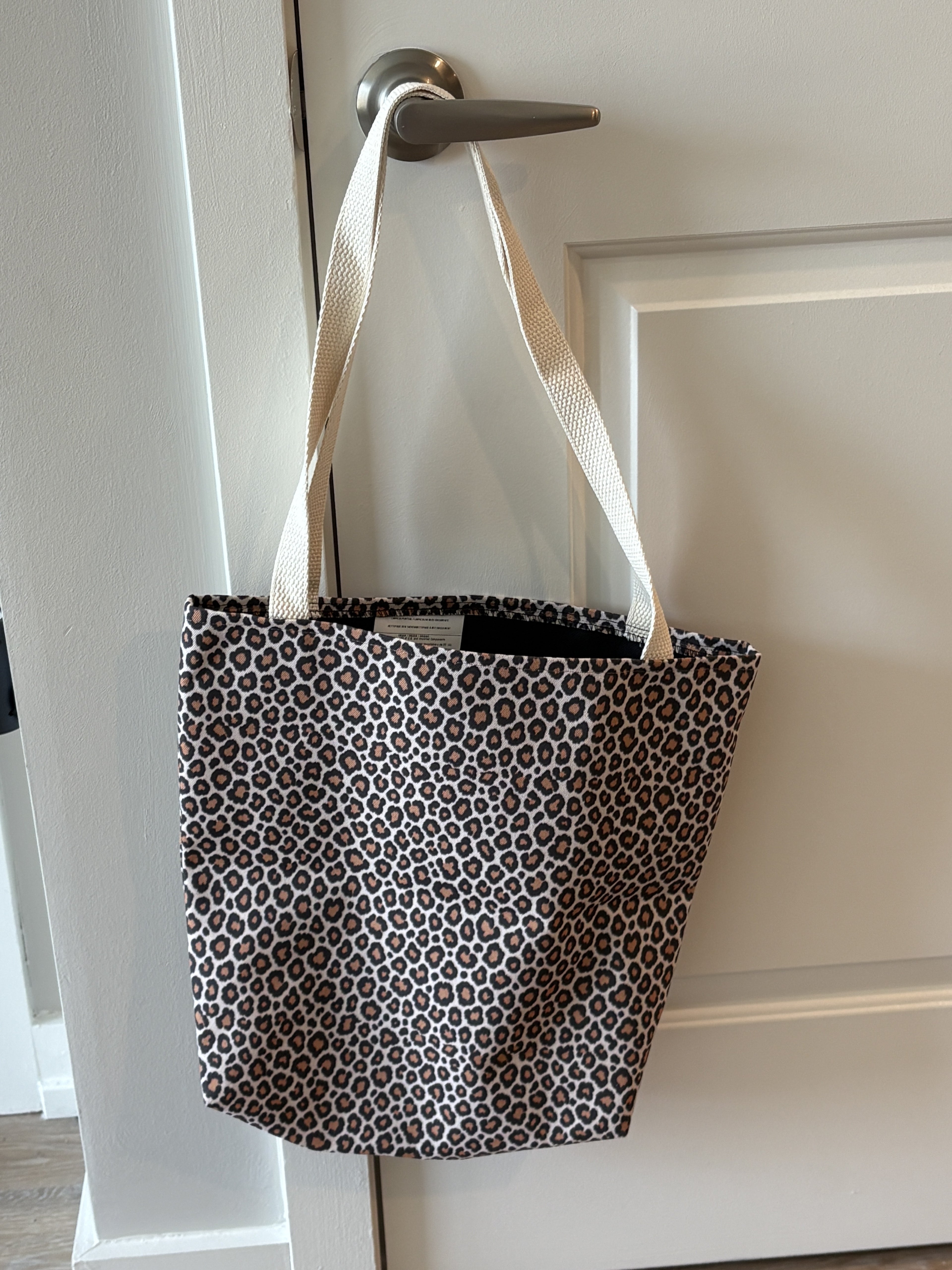 Tawny leopard print tote bag hanging — real product photo, styled