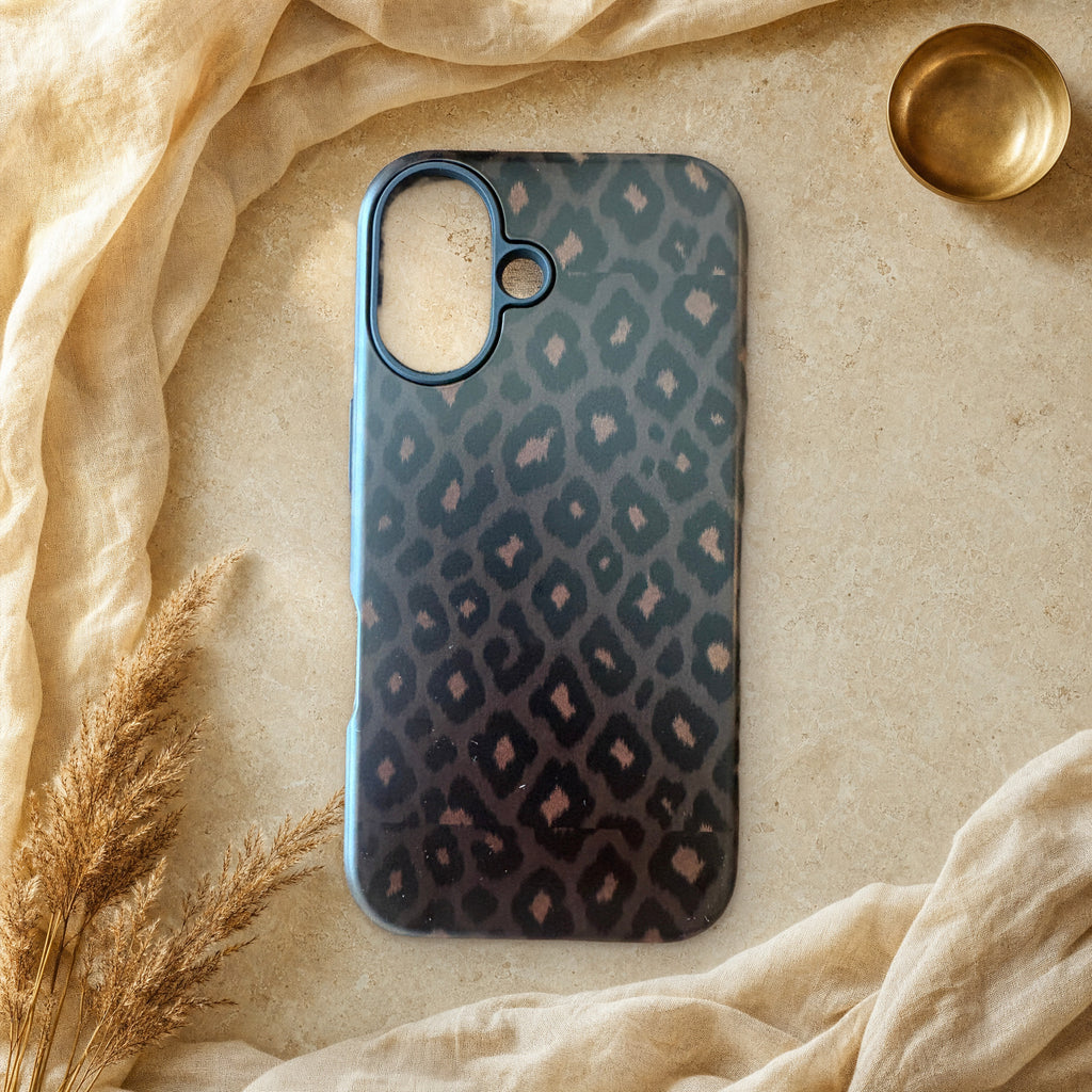 Black leopard print phone case lying flat on cream linen and travertine stone