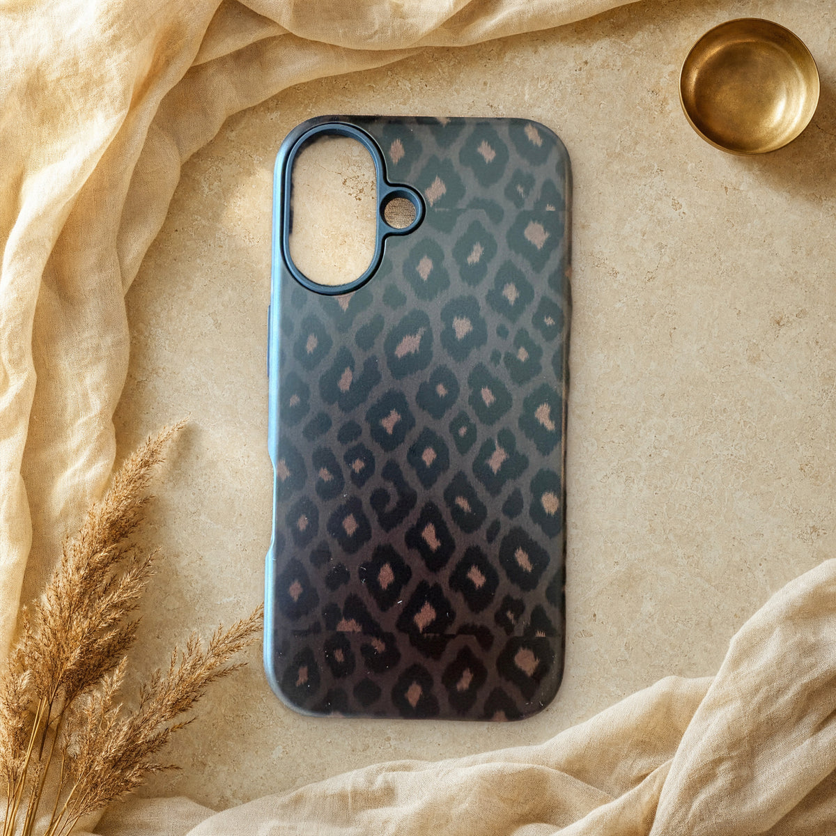 Black leopard print phone case lying flat on cream linen and travertine stone