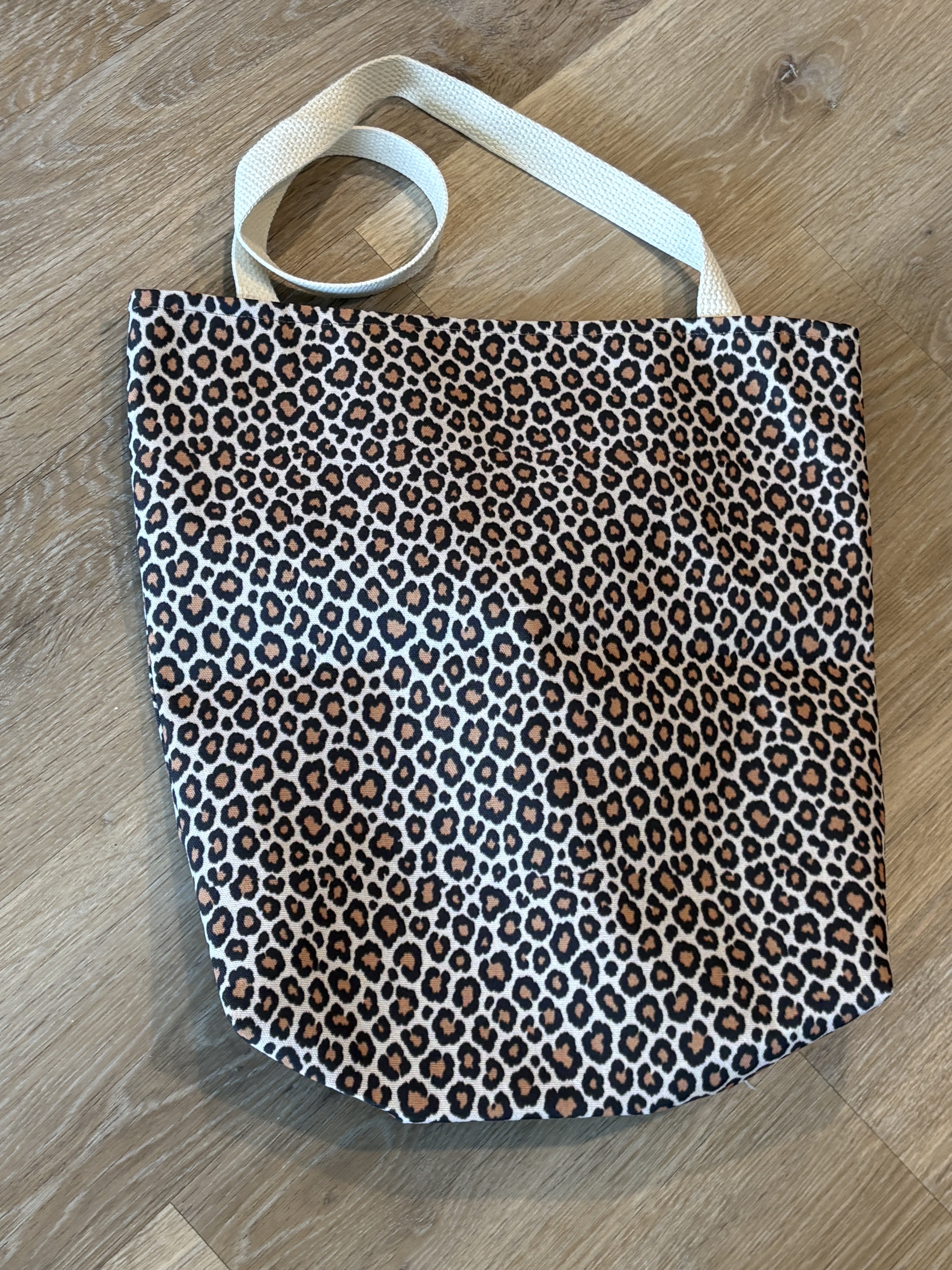 Tawny leopard print tote bag in warm cream — real product photo, flat lay