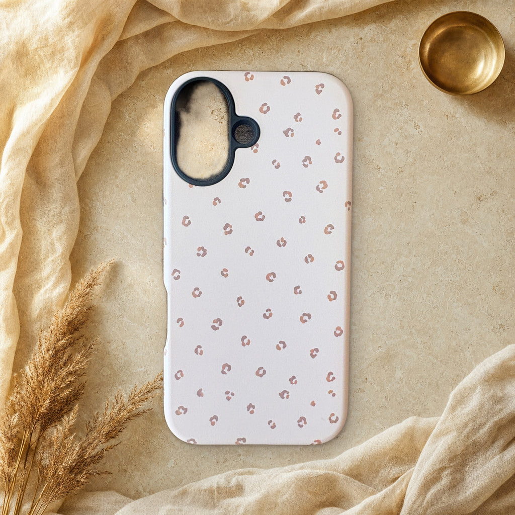 Soft blush pink leopard print phone case lying flat on cream linen and travertine stone