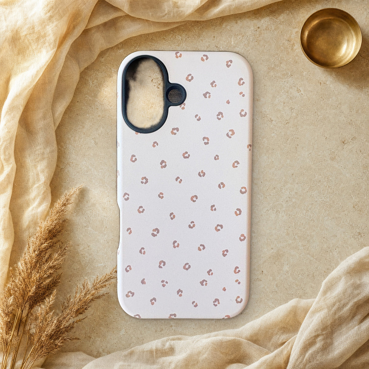 Soft blush pink leopard print phone case lying flat on cream linen and travertine stone