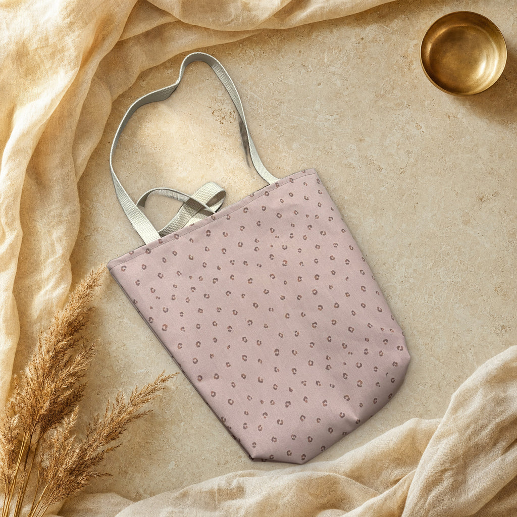 Blush pink spotted canvas tote bag laid flat on cream linen and travertine stone