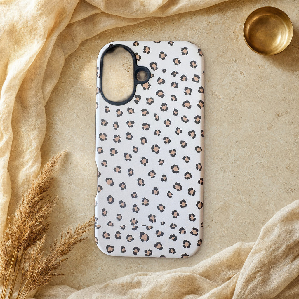 Warm neutral leopard print phone case lying flat on cream linen and travertine stone